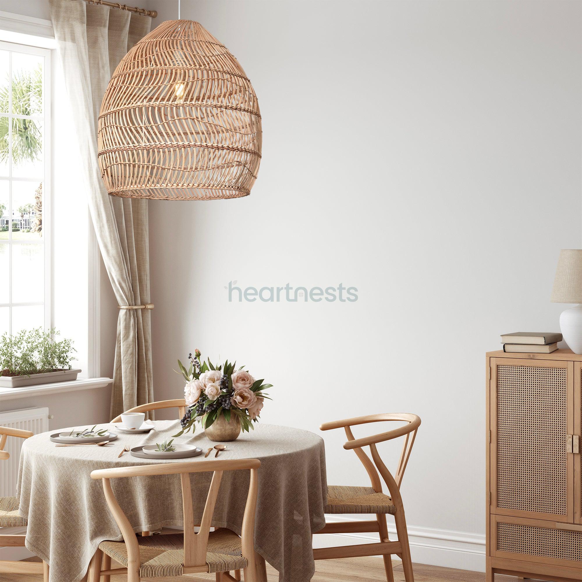Heart Nests's Acacia rattan pendant light is hung above a round dining table with gray table cloth and 4 rattan dining chair. A flower vase and 4 dishes with full cuttlery set up are on the table.