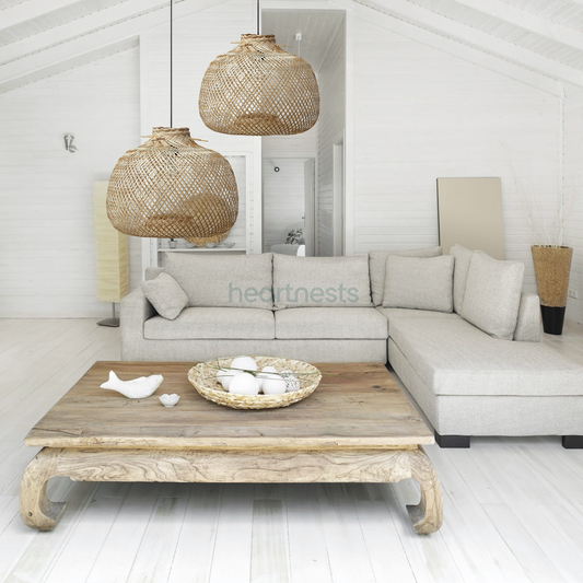 2 Bali bamboo pendant lights  from brand Heart Nests are hung in different heights above a wooden natural tone living room table and a light gray cloud chase sofa following coastal rustic style