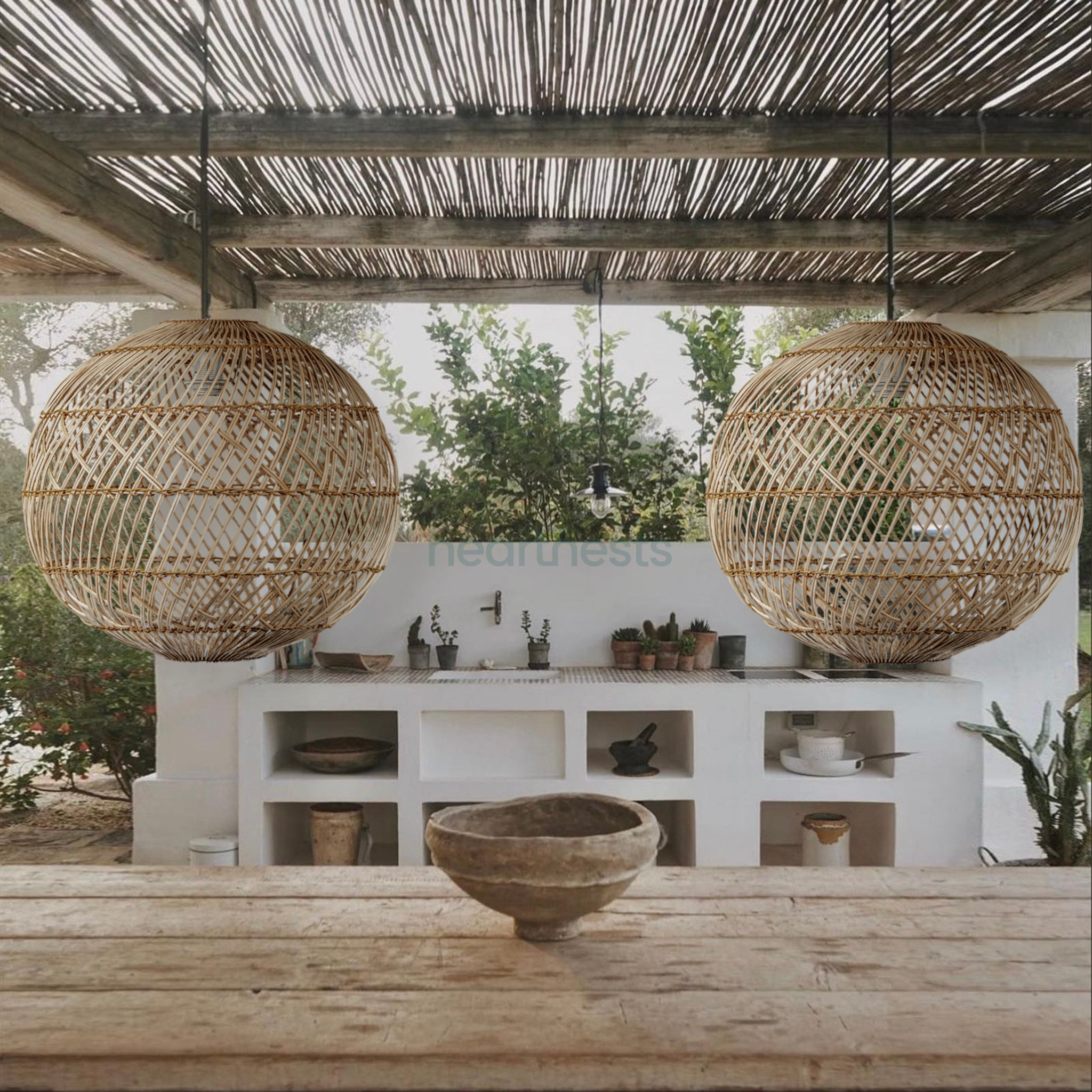 2 Ballia round shape rattan pendant lights from brand Heart Nests are hung above an outdoor wooden table in farmhouse style