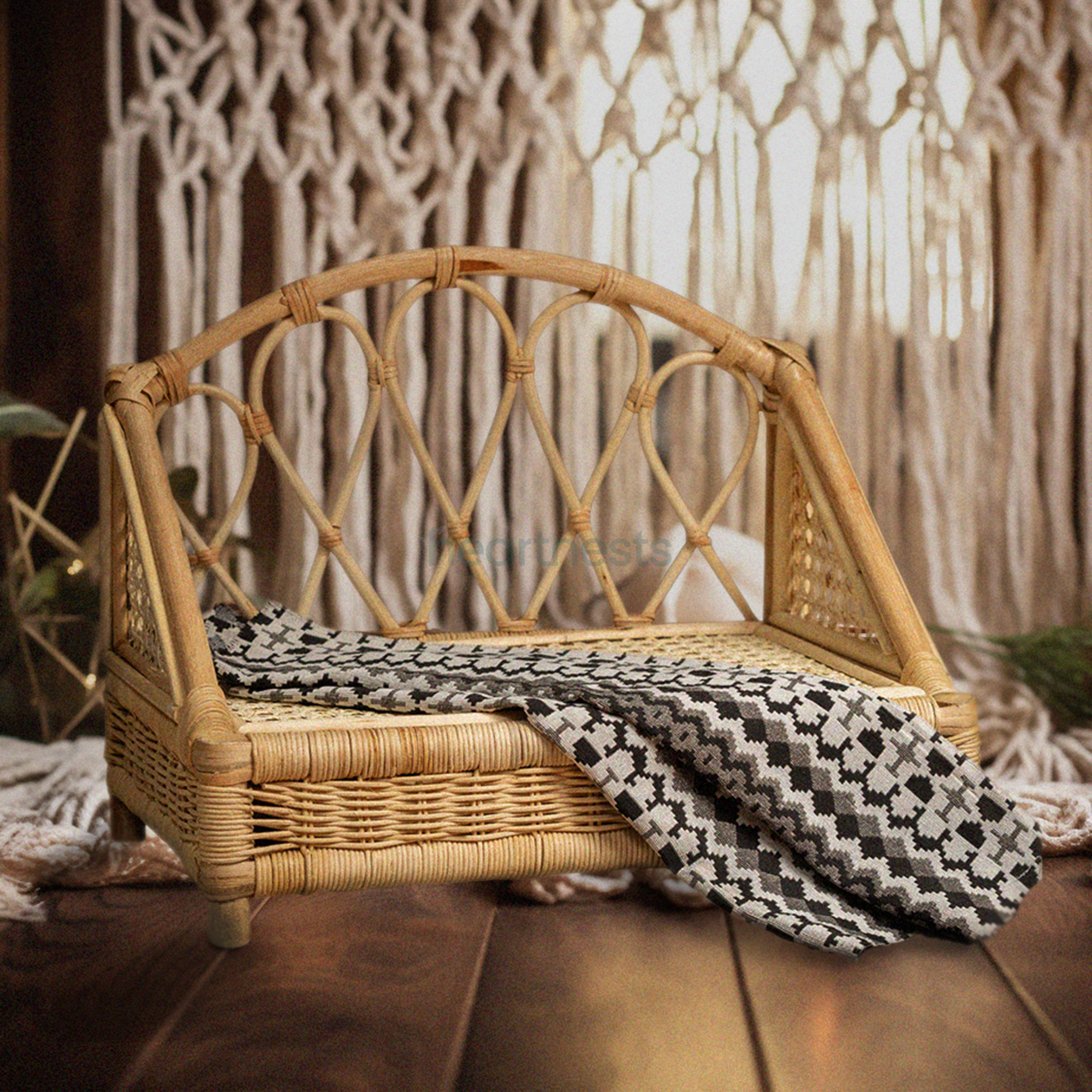 A Heartnests's Crown Rattan Newborn Prop is on a wooden floor and in front of a white macrame tassles