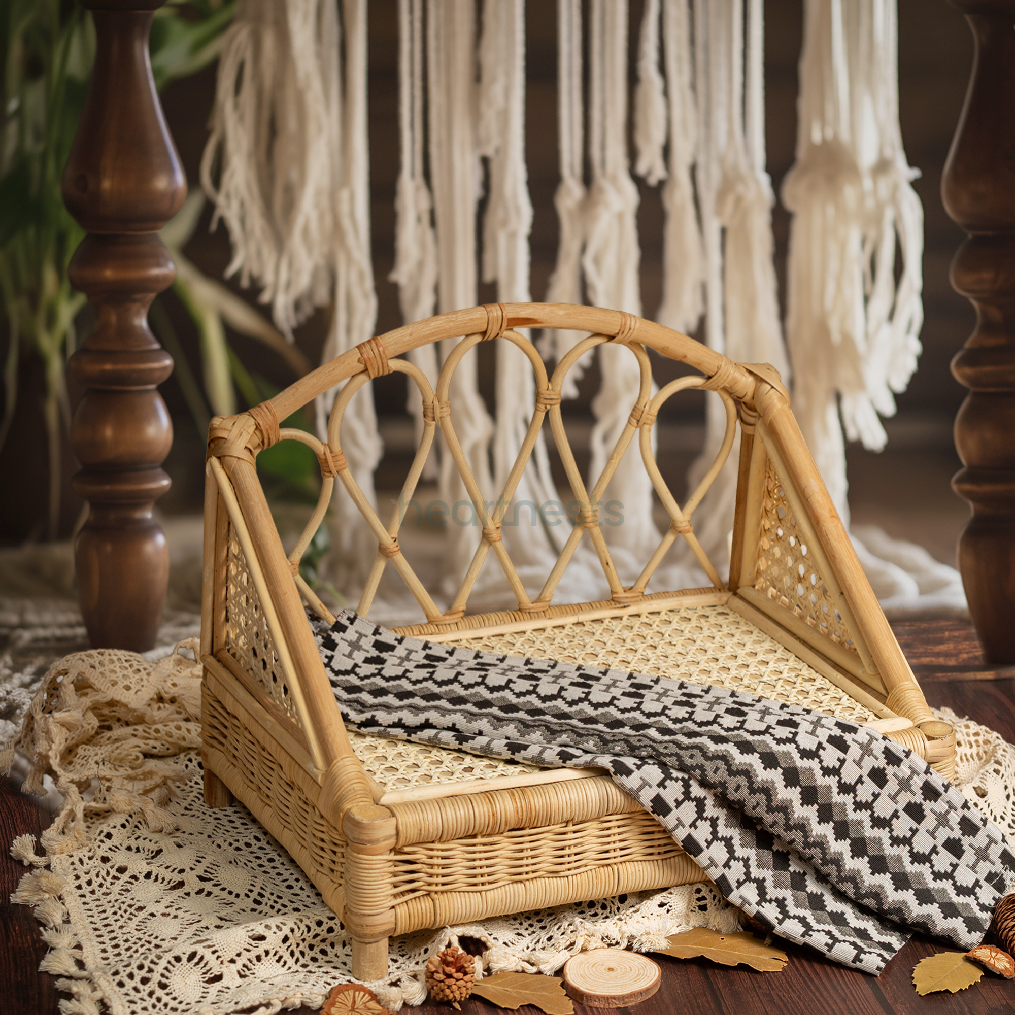 A Heartnests's Crown Rattan Newborn Prop is on a wooden floor and in front of a white macrame tassles