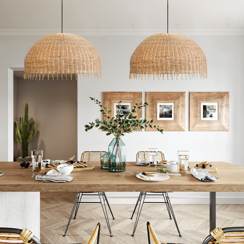 2 of Heartnests's Daria Rattan Pendant Lights are hung above a wooden dining table with 2 rattan chairs in a contemporary decor setting
