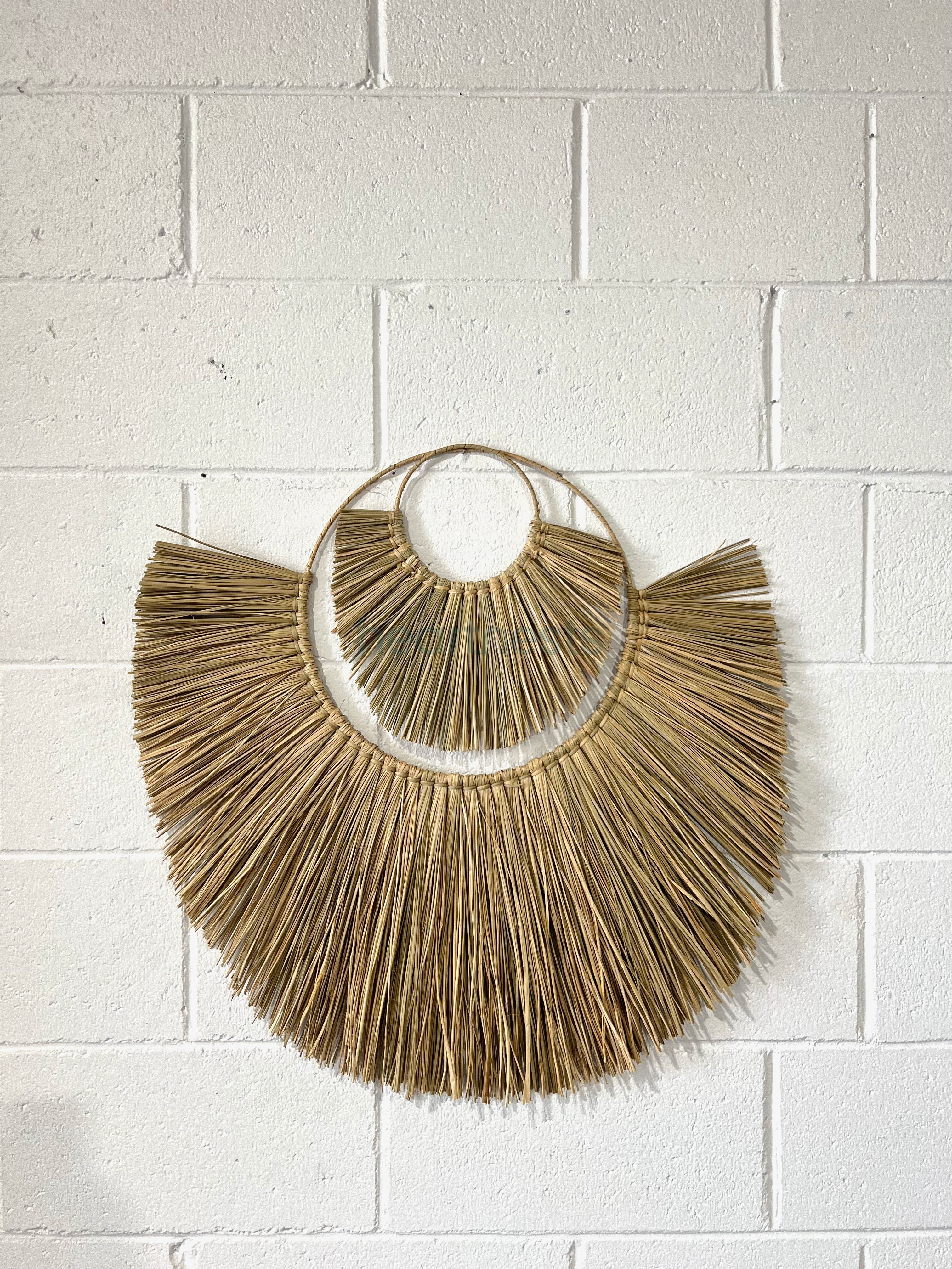 Heartnests' Moon Seagrass Wall Decor in size Large and Small are on a white brick wall