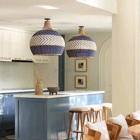 Two of Heart Nests' Cosmo rattan hanging lights are hung side by side over a blue tone kitchen island in a boho style kitchen