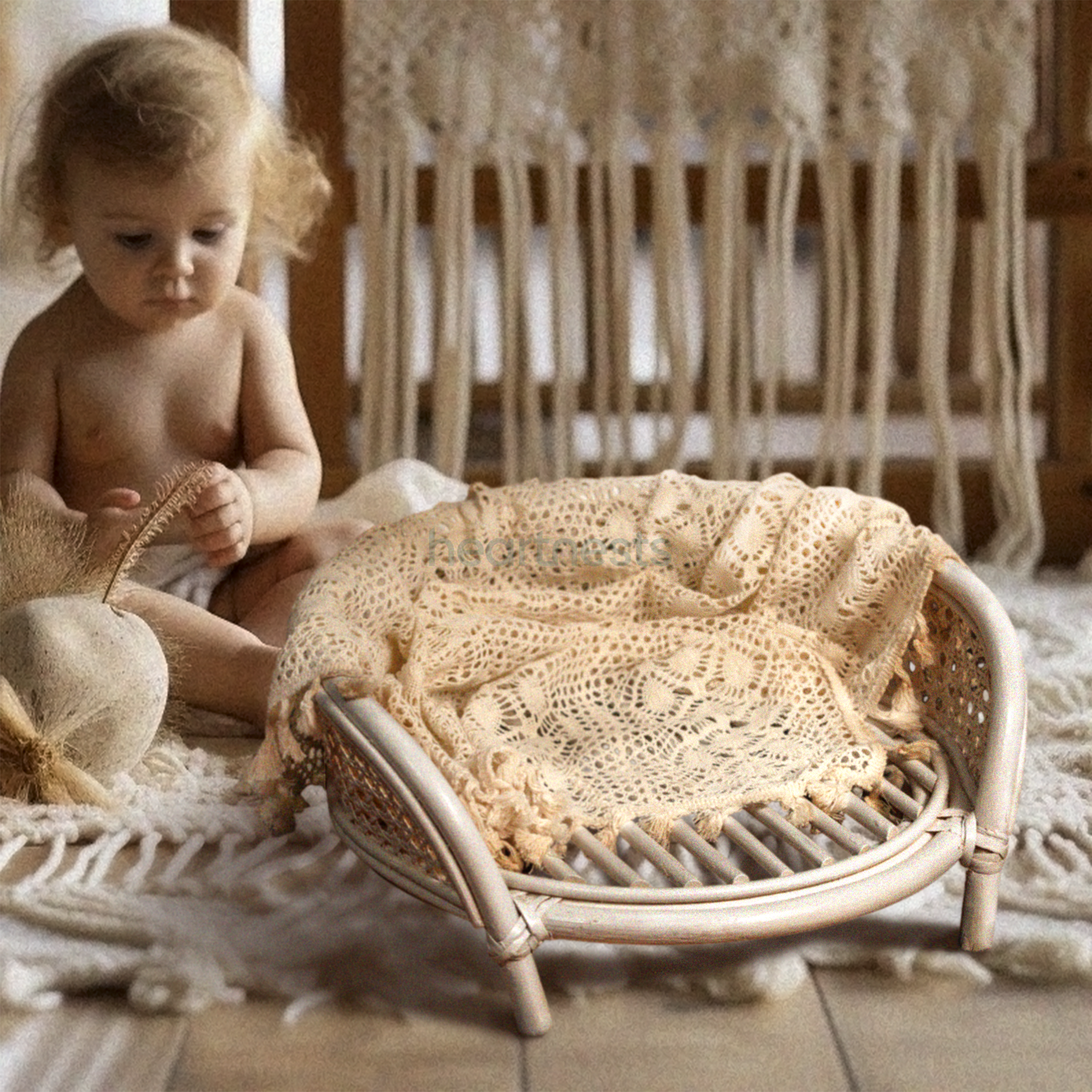 A Heartnests' Lilly Rattan Newborn Prop in cream color is placed in front of a baby and a white macrame