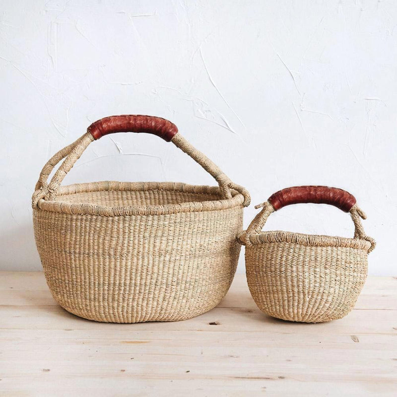 Heartnests' Picnic Bolga Seagrass Baskets in Large and Small Adult size are placed side by side on a wooden surface against a white wall