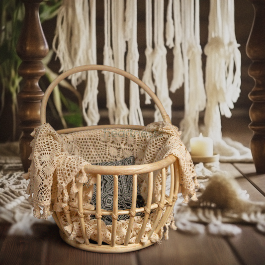 A Heartnests' Kira Rattan Baby Prop Basket with handles is placed on a dark brown wooden flooring and in front of a white macrame