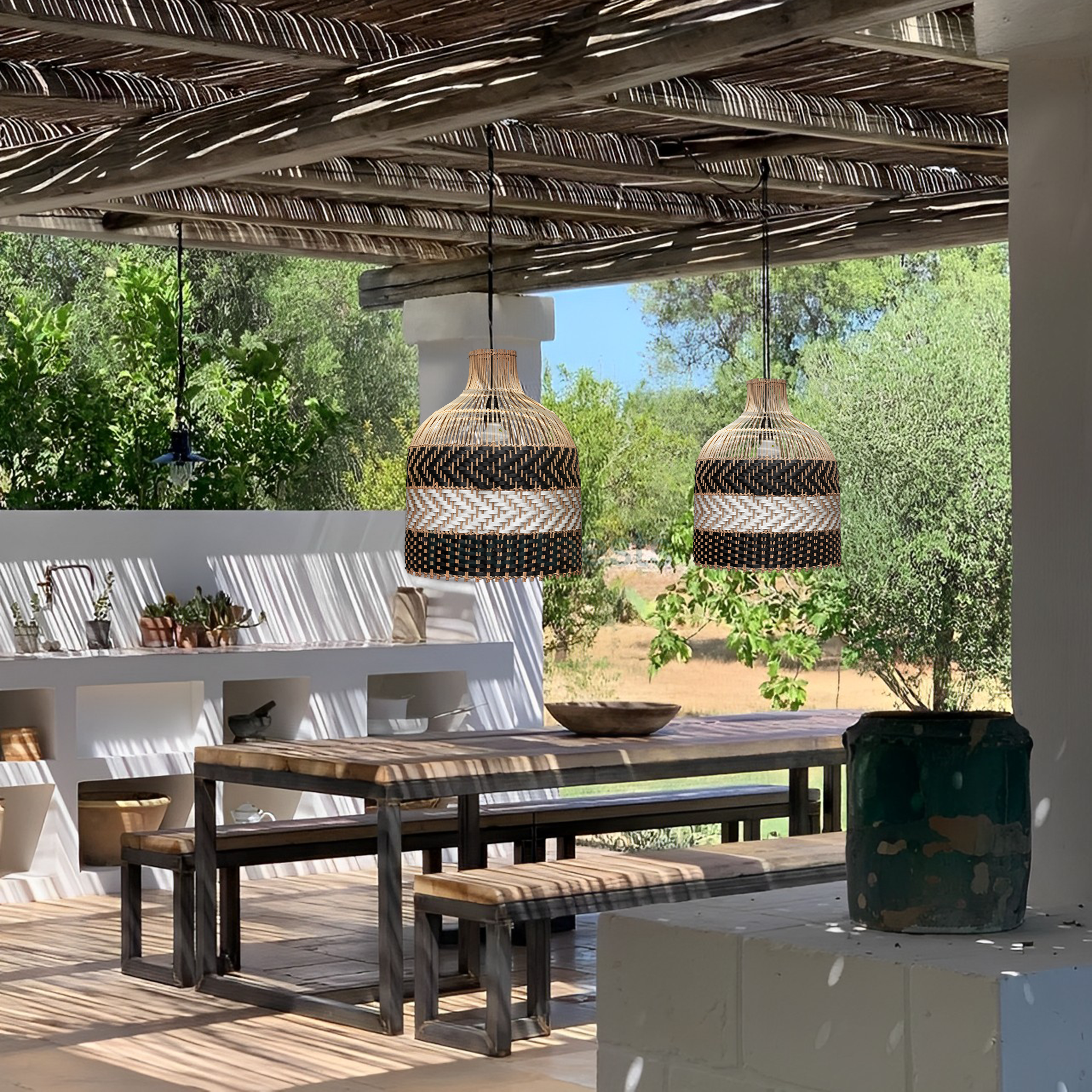 2 of Heartnests' Luka Rattan Pendant Lights are hung above an outdoor rectangular dark brown wooden table and 2 benches under a covered patio