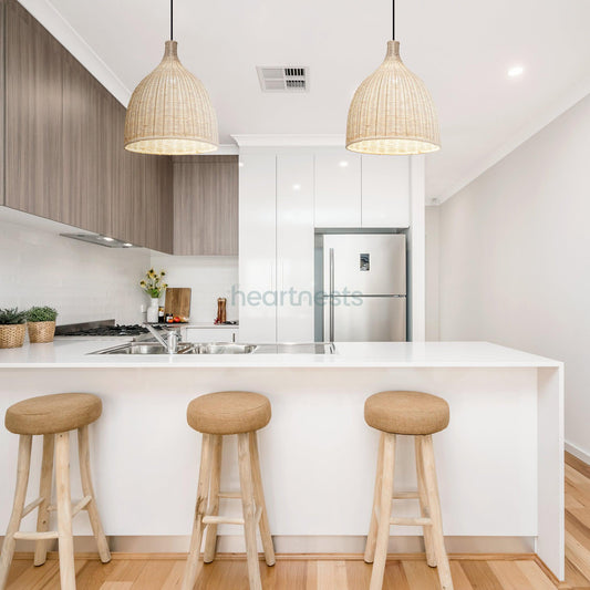 2 of Heart Nests's Baleria Rattan hanging lights are hung side by side over a kitchen island with white marble top next to 3 wooden stools, inspired contemporary interior style