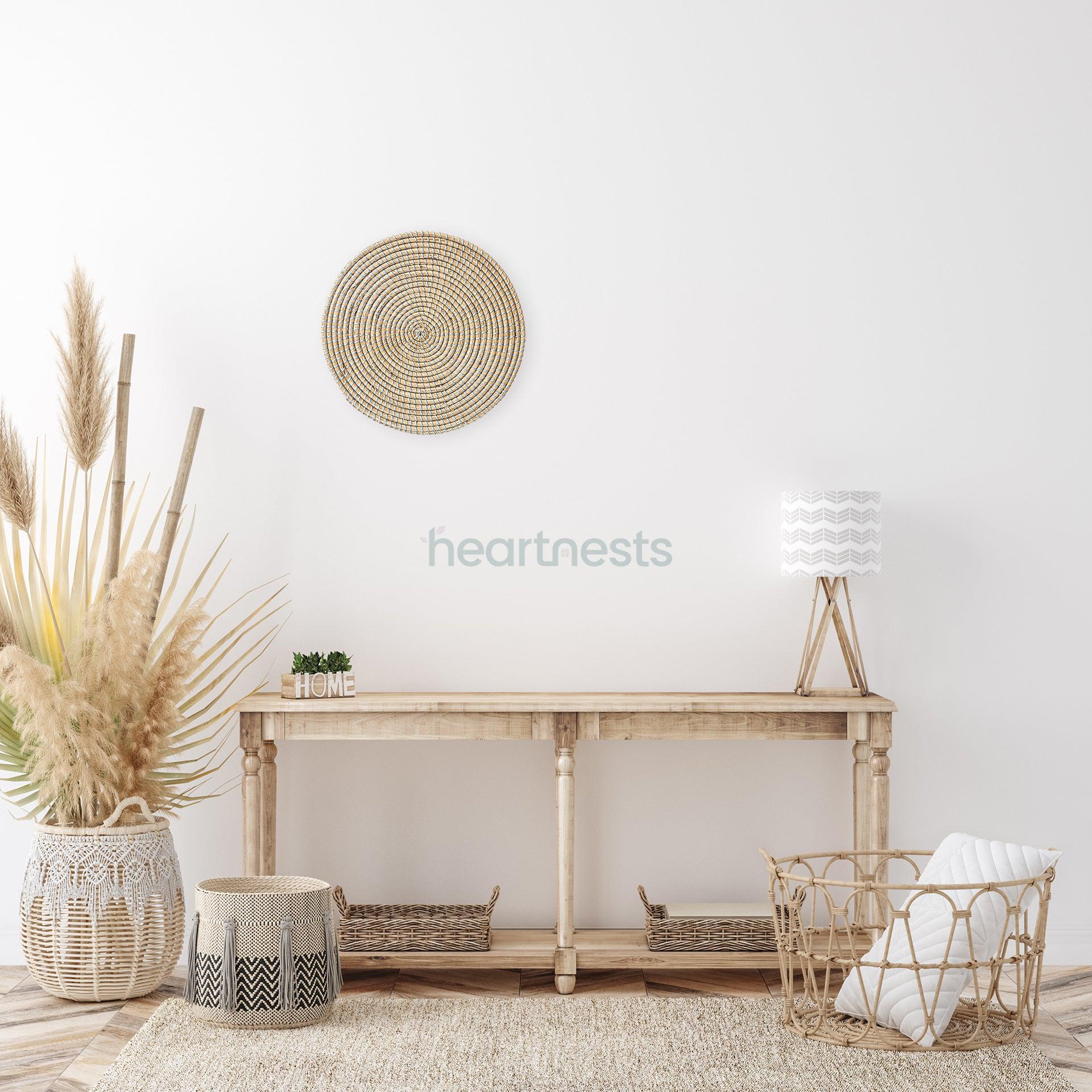 Heartnests' Ricey Handmade Seagrass Wall Decor is hung on a beige color wall above a wooden rustic console table with a table lamp placed on a seagrass rug with decorative flower pots and rattan laundry basket
