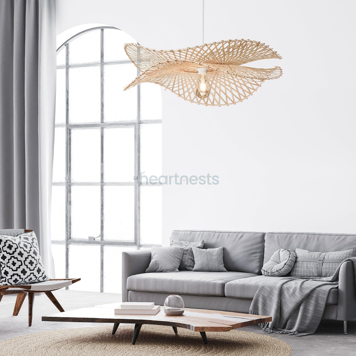 A Heartnests's Correa Bamboo Hanging Lampshade is hung above a contemporary wooden living room table and a 2 seater grey lounge