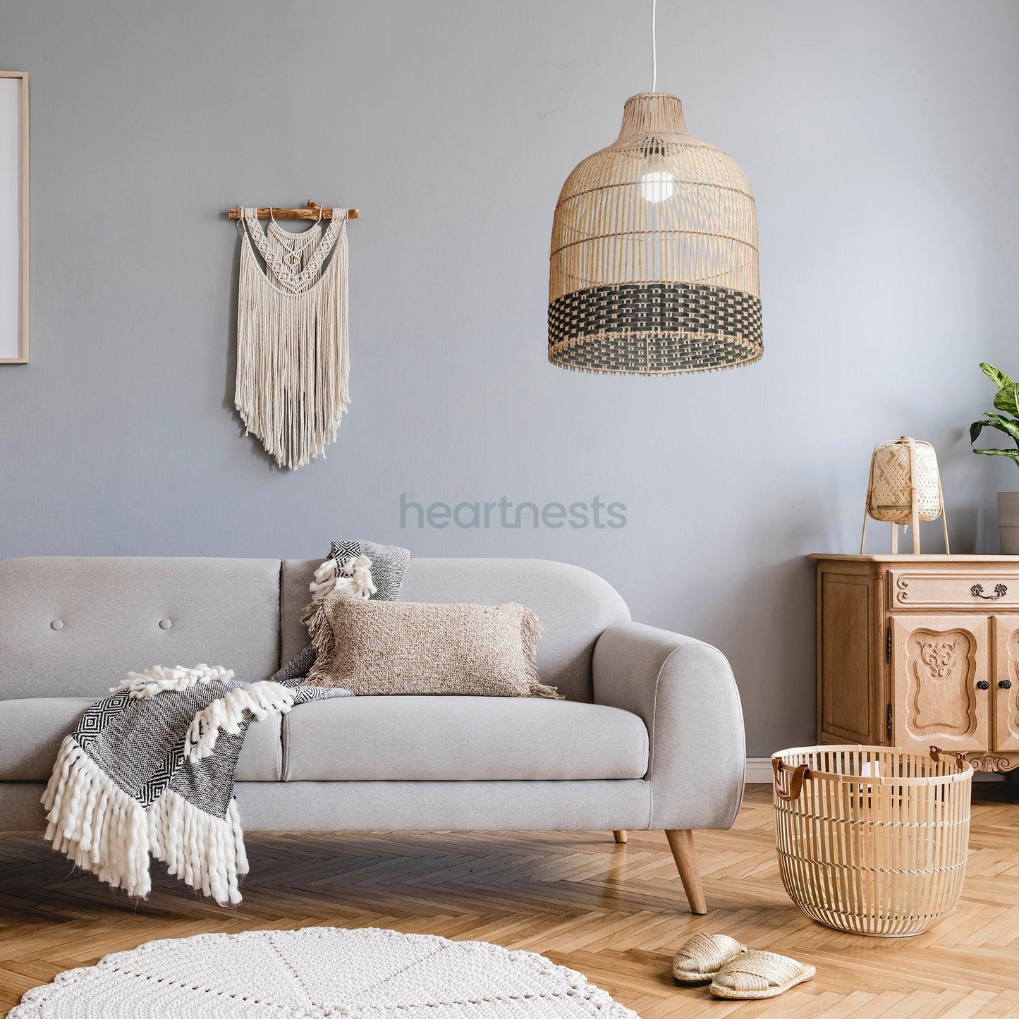 Heartnests's Ayla rattan hanging light is hung above a small round wooden living room table and a gray tone sofa. A white macrame is hung on the wall