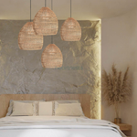 A cluster of 4 of Heart Nests's Acacia rattan pendant light is hung above a wooden bed with white bed sheet against a gray brick accent wall, in a modern boho rustic style bedroom.
