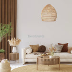 A Heart Nests's Acacia rattan pendant light is hung above a white 2 seater sofa and a round rattan table in a simple boho living room 