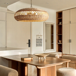 The Almafi rattan hanging light is hung above a minimalistic dining wooden table