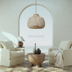 A Bali wicker lampshade from brand Heart Nests is hung above 2 beige sofas in a coastal modern living room with ocean view