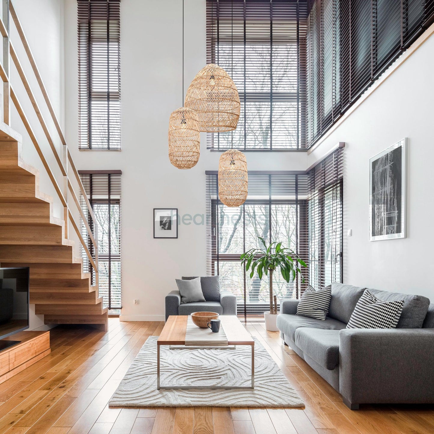 1 Brighton Rattan Pendant Light and 2 Moreton Rattan Pendant Light by Heart Nests brand are hung in a modern luxe setting, next to a stair case and above a living room table and gray sofa