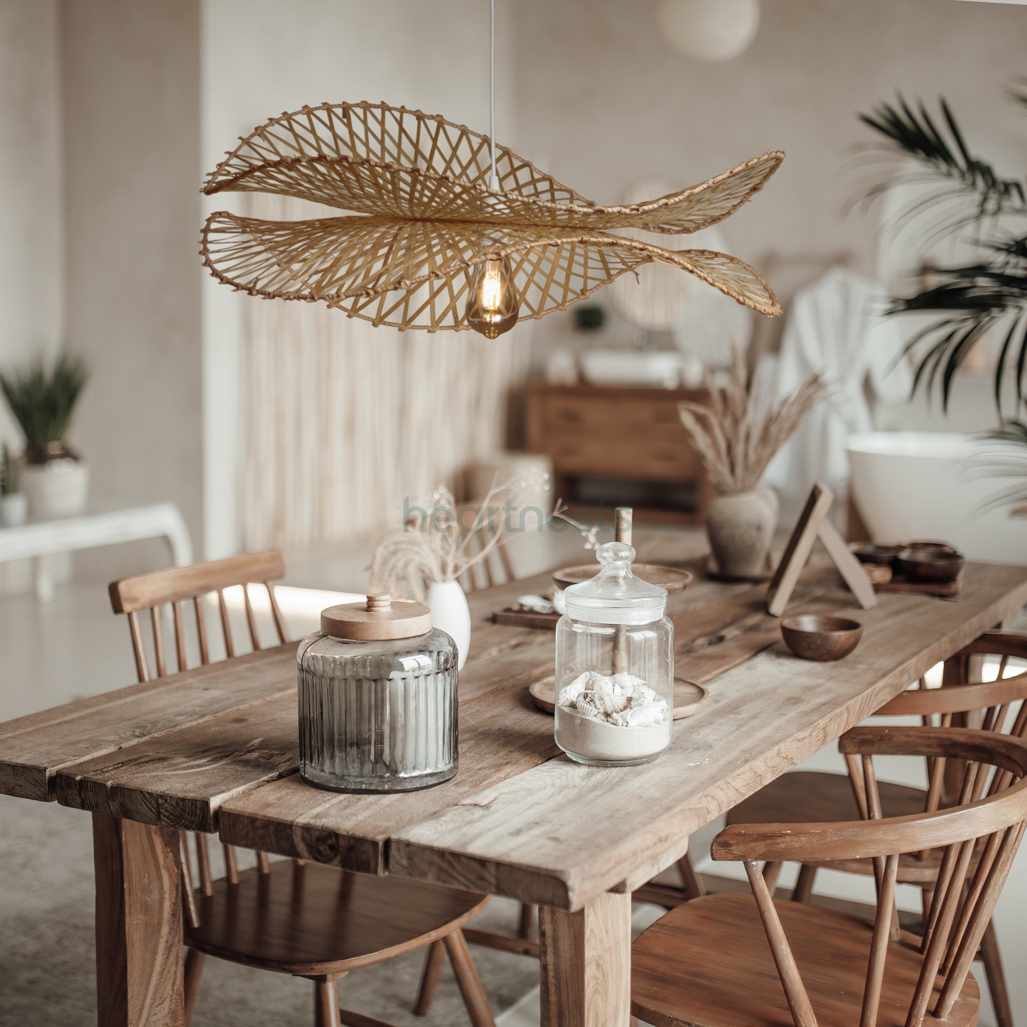 A Heartnests's Correa Bamboo Hanging Basket is hung above a wooden boho style dining table with