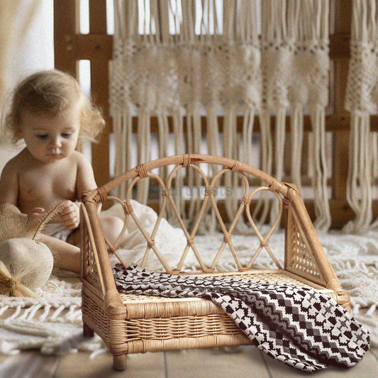 A Heartnests's Crown Rattan Baby Prop is next to an adorable baby and a white macrame as a background