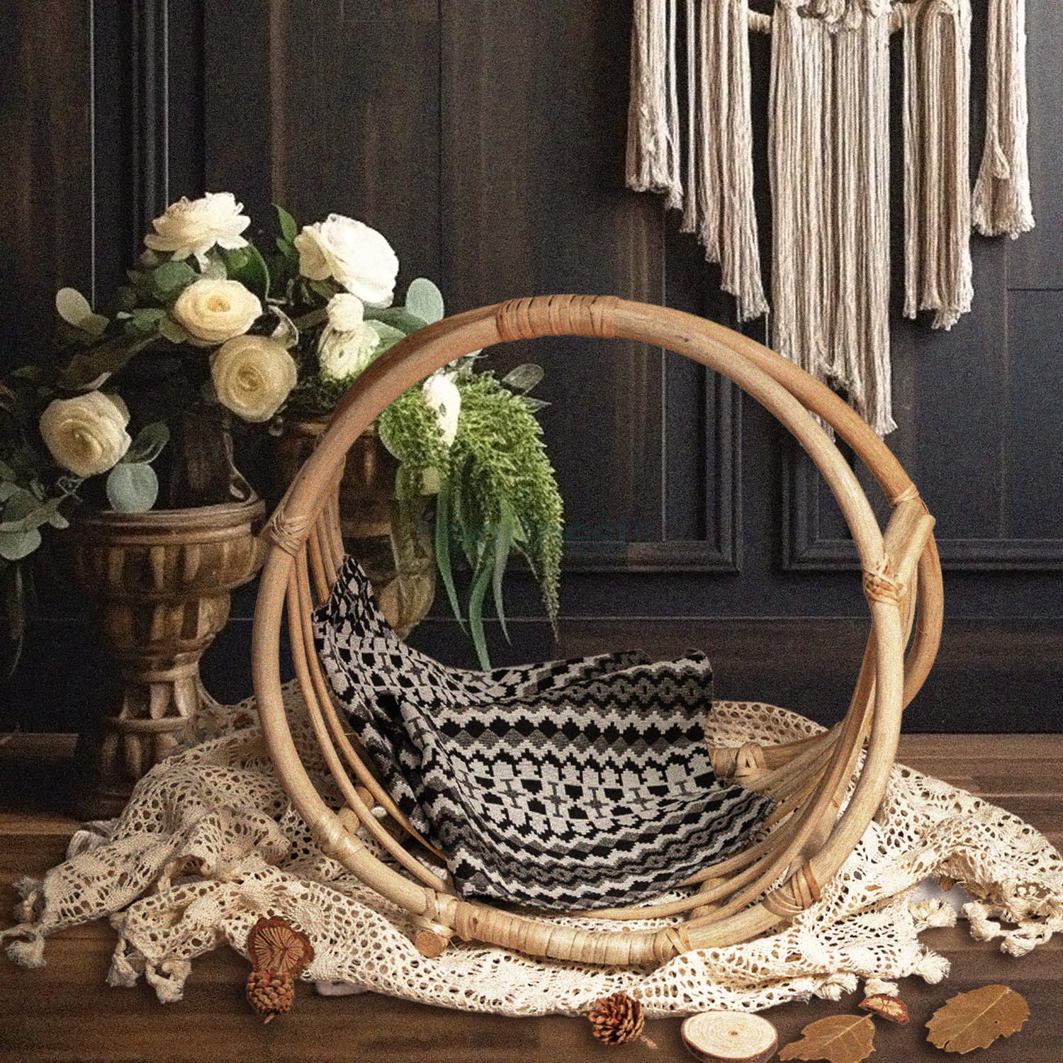 A Heartnests's Rattan Baby Photography Prop is placed on a white macrame and in front of a white dream catcher next to a beautiful white flower vase