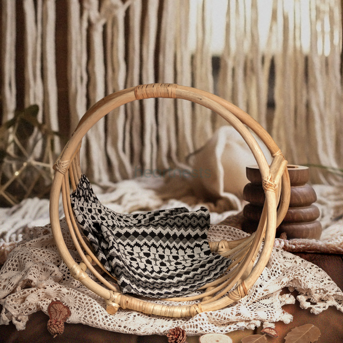 A Heartnests's Wicker Newborn Photography Prop is placed on a white macrame and in front of dropping down macrame tassles next to a beautiful white flower vase