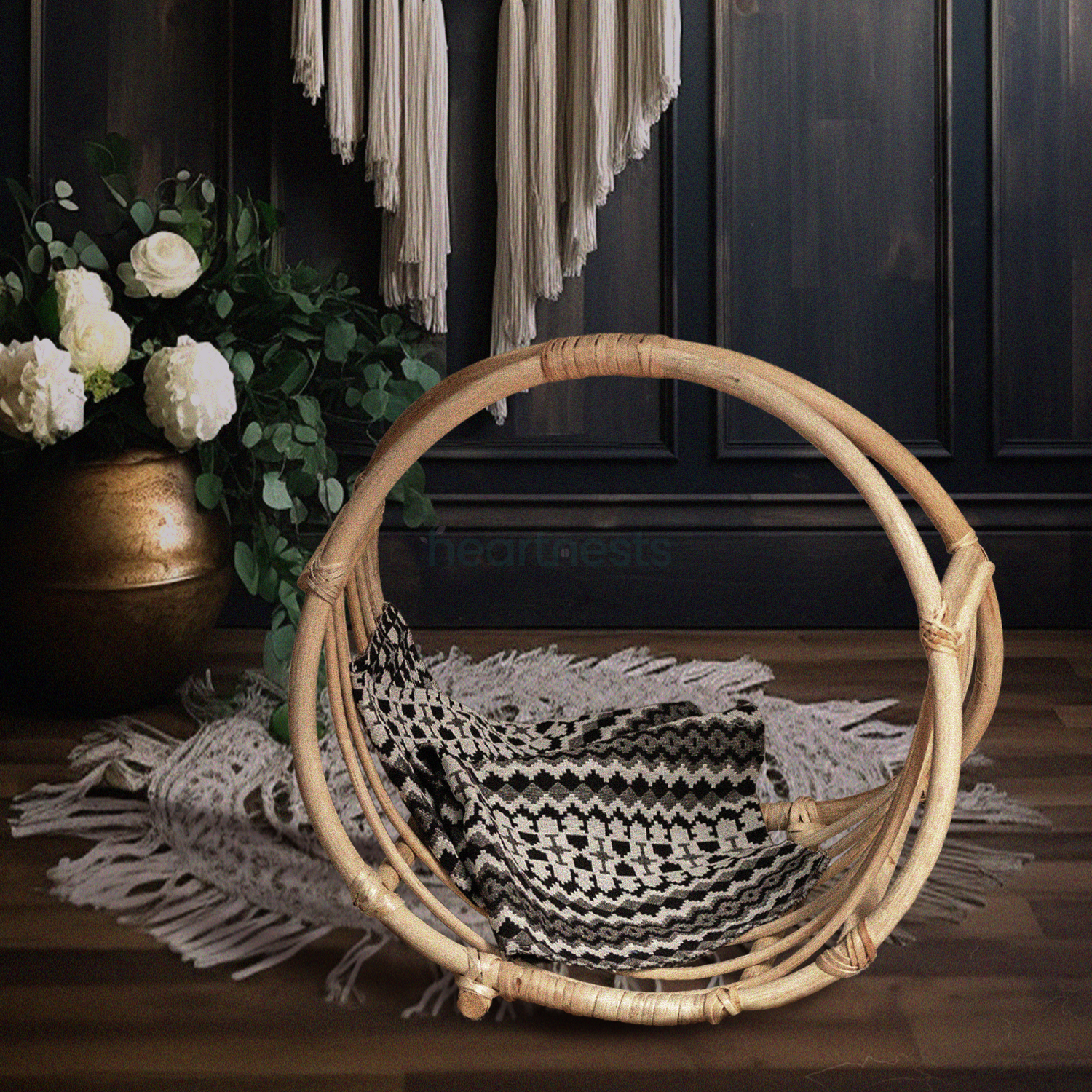 A Heartnests's Rattan Baby Photography Prop is placed on a white macrame next to a beautiful white flower vase