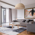 A Heartnests's Daria Rattan Lampshade is hung above a living room table with a grey lounge in a contemporary living room decor setting