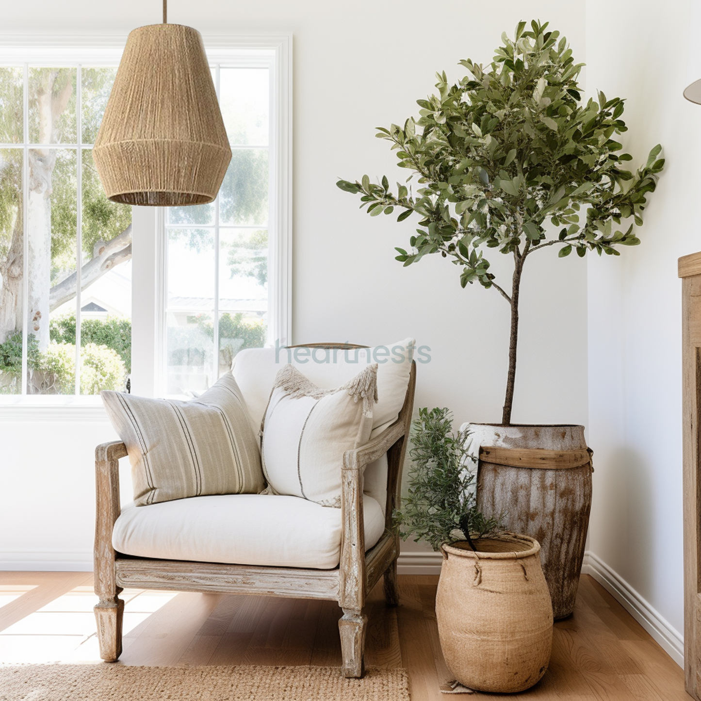 A Heartnests's Long Diamond Jute Hanging Light is hung above a wooden grey wash arm chair next to an olive tree pot plant