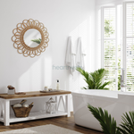 A Heartnests' Flora Rattan Mirror is hung on a white wall above a white storage shelves next to a large window and a pot plant
