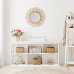 A Heartnests' Flora Rattan Mirror is hung on a white wall above a white storage shelves following boho chic room design concept