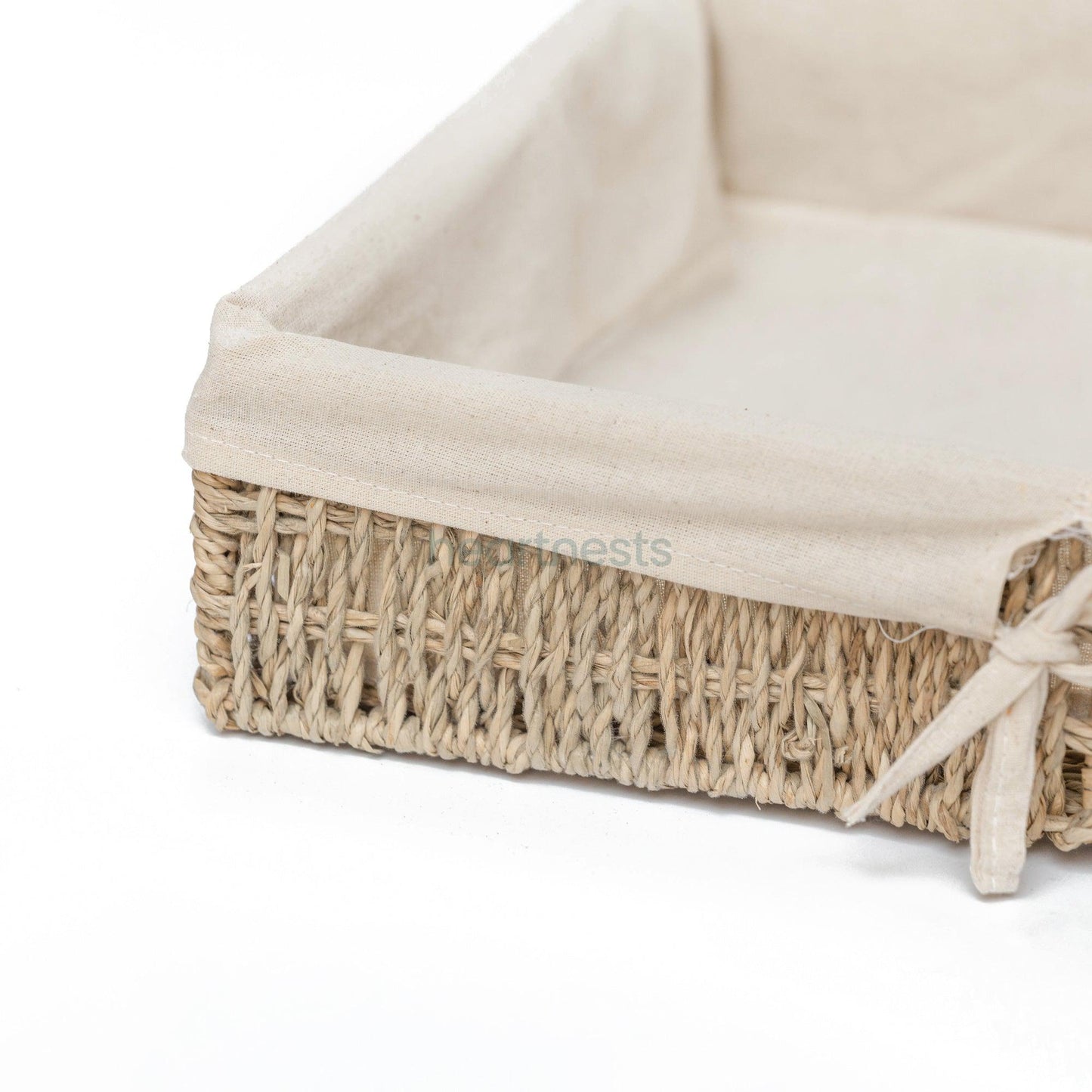 A zoomed in left corner part of a Heartnests' Mimi Storage Seagrass Basket with cotton liner is on white background