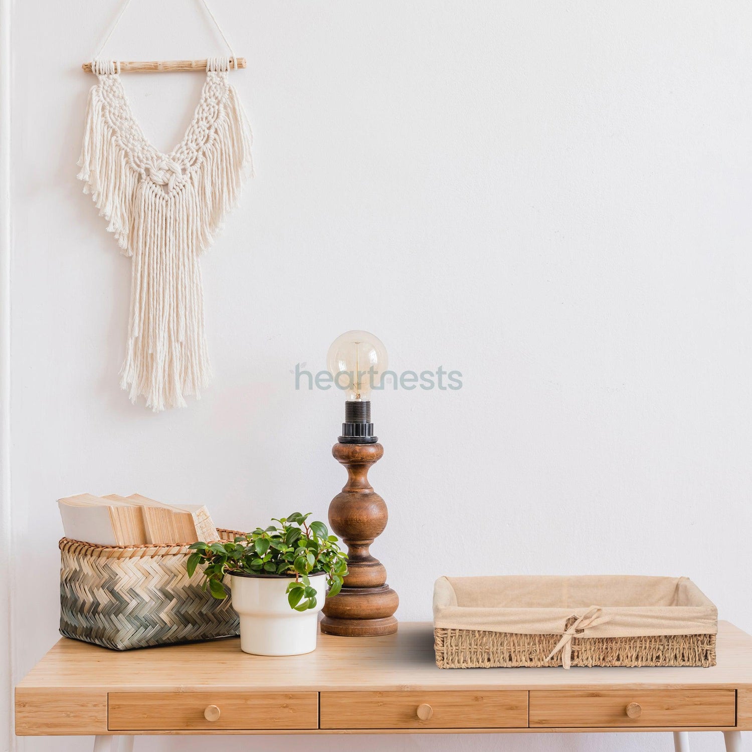 A Heartnests' Mimi Seagrass Storage Basket with liner is on a hallway table with a candle holder and a mini pot plant. There's a macrame hung on the wall