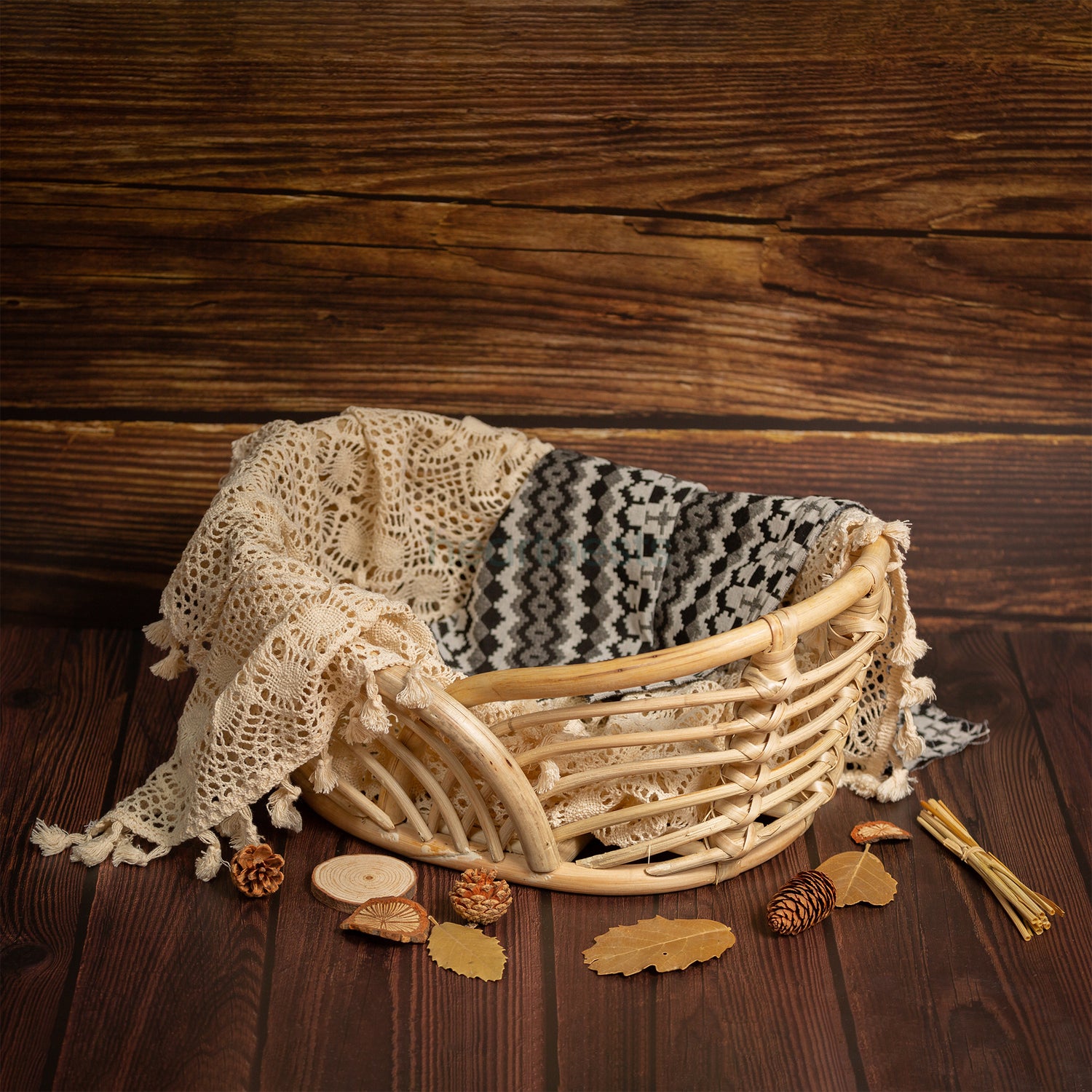 A Heartnests's Noah Rattan Baby Prop is half covered by a white macrame placed on a woodem floor with toys and flowers