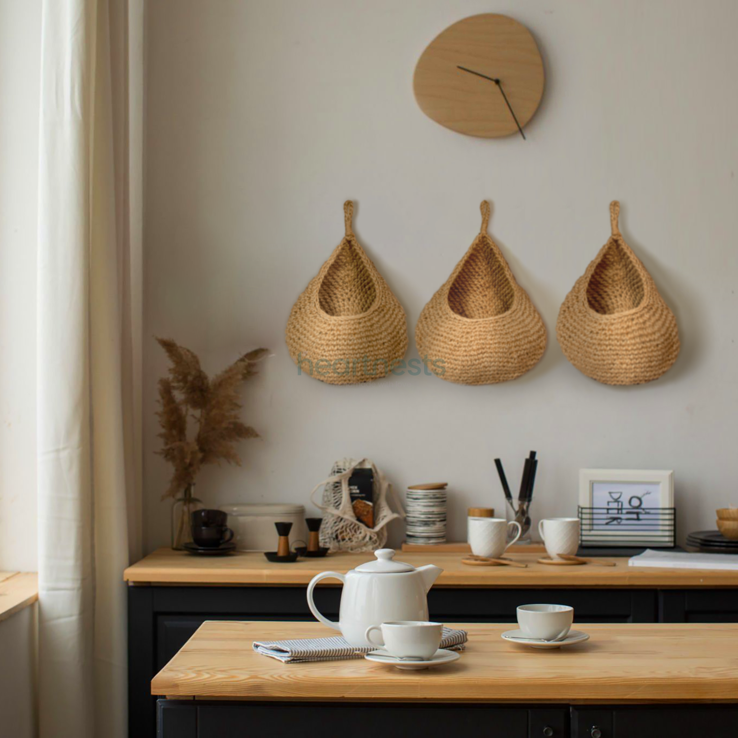 3 of Heartnests' Onia Seagrass Hanging Baskets are hung on a kitchen wall above a wooden console table in a kitchen with a wooden dining table