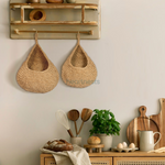 2 of Heartnests' Onia Seagrass Wall Baskets are hung side by side from a wall hook above a wooden console table