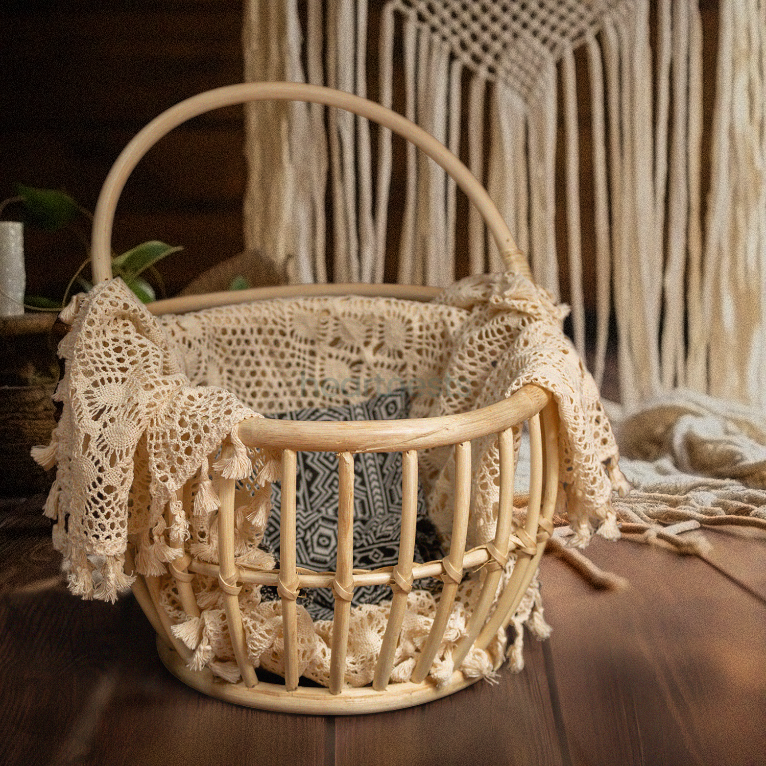 A Heartnests' Kira Rattan Newborn Photography Basket with handles is placed on a dark brown wooden flooring and in front of a white macrame