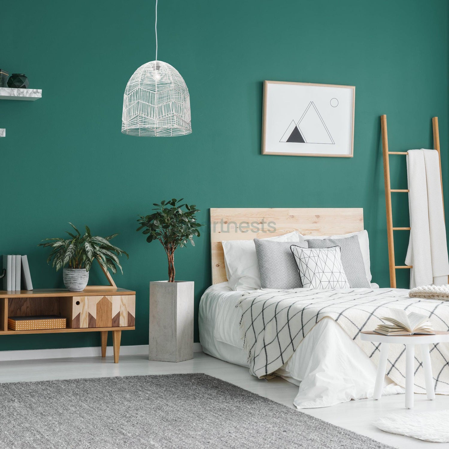 Whitewash Lacy rattan lace pendant light is hung above a bedside table and a pot plant. The room is painted green