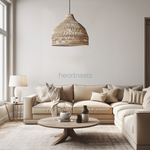 A Heartnests' Lombok Seagrass Wicker Pendant Light is hung above a wooden round table and a 3 seater light grey color sofa