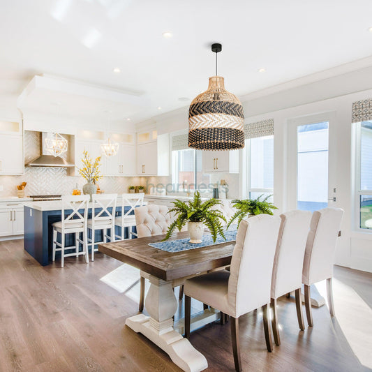 A Heartnests' Luka Rattan Pendant Light is hung above a rectangular dining table with 6 light grey dining chairs in a contemporary bright living room with blue hue kitchen island