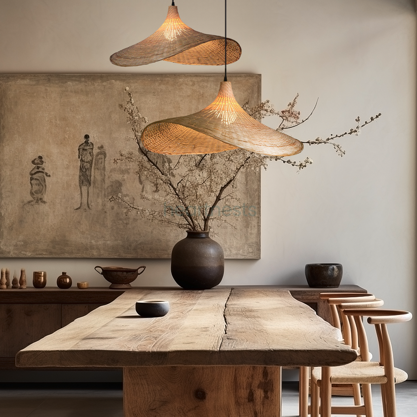 2 of Heartnests' Mexica Wicker Pendant Lights in curved hat shape are hung above a rustic style wooden kitchen island and a terra cotta vase with branches. There's a neutral tone rustic style painting on the kitchen wall